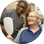 the doctor with a male patient holding a hand mirror
